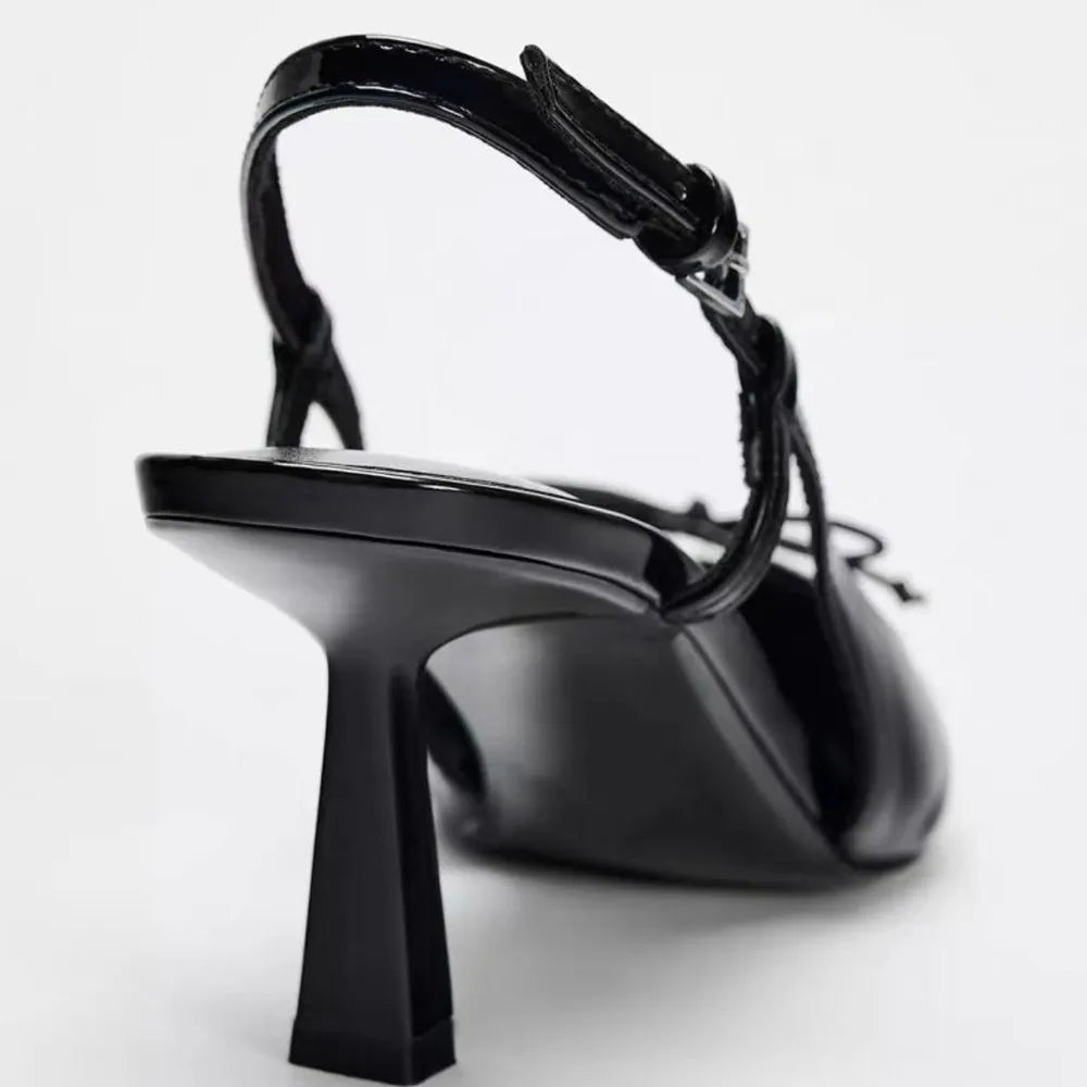 Black patent leather bow with pointed tip thin heel and a shallow strap for women's sandals